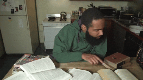 A man studies, jumping around from book to book rapidly. 