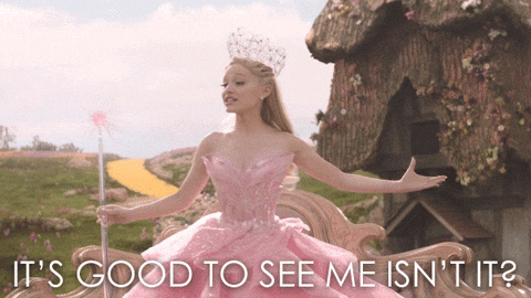 Ariana Grande as Glinda in Wicked, saying, "It's good to see me, isn't it?"