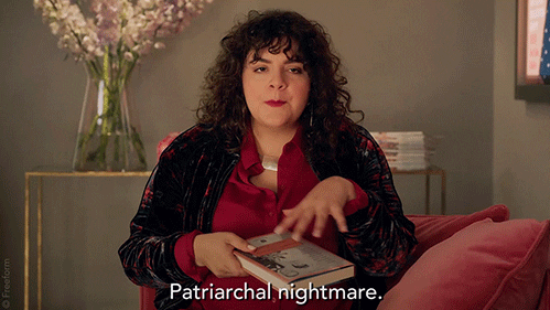 A woman with curly brown hair says, "patriarchal nightmare." 